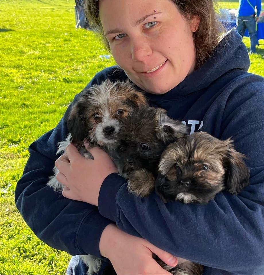a woman holding three puppies in her arms